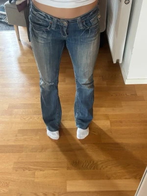 Blå bootcut jeans med slitningar - Märker big star, blå Low Rise jeans med hål på ena knät, litet hål på rumpan men har tyg under hålet.