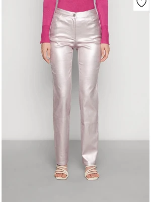 Metallic rosa raka byxor  - Säljer ett par metallic rosa jeans från NA-KD  med rak passform och hög midja. Byxorna har klassisk femficksdesign och stängs med knapp och dragkedja. Materialet är glansigt med lite skimmer. Använd en gång. 