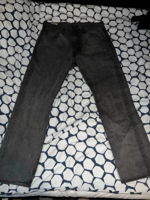 Grå raka jeans från Levi's 501 - Säljer ett par grå Levi's jeans med rak passform och klassisk femficksdesign. Jeansen har en diskret tvätt och är tillverkade i slitstark denim. Perfekta för en avslappnad och stilren look. W=32 L=30
