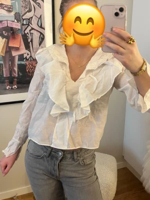 Vit blus med volanger och spetsdetaljer - Säljer en superfin vit blus från Zara med stora volanger framtill och spetsdetaljer vid kragen. 