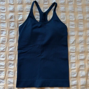 Mörkblå ribbad linnetoppt - Snygg mörkblå ribbad linnetopp med brottarrygg. Stretchigt och följsamt material som sitter skönt mot kroppen🦋
