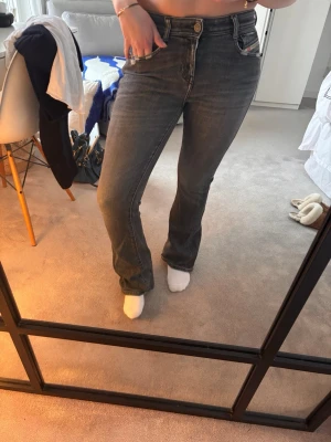 Low/mid-waist bootcut jeans från diesel  - Säljer ett par grå jeans från Diesel med bootcut ben och klassisk modell. Jeansen har en snygg tvättad look och detaljer som logga på fickan. Perfekta för dig som gillar en avslappnad men ändå stilren vibe. W28 längd står inte men passar mig perfekt som är 160