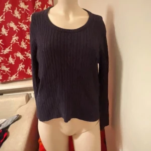 Mörkblå stickad tröja från Prêt - Mörkblå stickad tröja från Prêt med rund halsringning och diskret kabelstickat mönster. Tröjan har långa ärmar och en klassisk, enkel design som passar till det mesta. Perfekt för dig som gillar stilrena plagg med en mysig känsla.