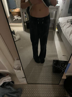 Svarta vida mjukisbyxor med dragsko - Säljer ett par svarta mjukisbyxor med vida ben och dragsko i midjan. Byxorna har en avslappnad passform och är perfekta för chill dagar. Tillverkade i mjukt material som känns skönt mot huden. Passar dig som gillar en casual och bekväm stil.