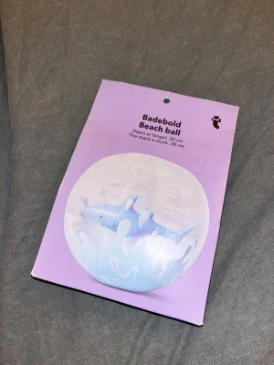 Badboll - Säljer en uppblåsbar badboll med en haj som är fångad i den- diameter 30 cm. Badbollen är genomskinlig med blå detaljer och en haj inuti. Perfekt för stranden eller poolen. Kommer i originalförpackning- helt ny