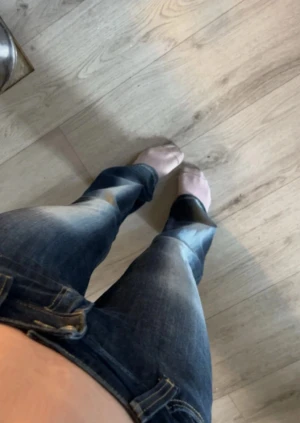 Blå bootcut jeans  - Säljer ett par blå bootcut jeans med snygga slitningar och ljusa tvättade partier på framsidan. Storlek 25/32