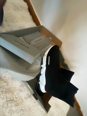 Balenciaga Speed Trainer svarta sneakers - Säljer ett par svarta Balenciaga Speed Trainer sneakers med vit chunky sula och stickad ovandel i textil. Skorna har en strumpliknande passform och Balenciaga-logga på sidan. Perfekta för dig som gillar streetwear och vill ha något riktigt trendigt.