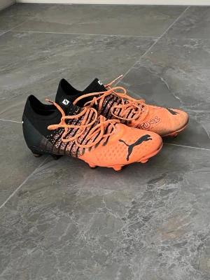 Puma Future orangea fotbollsskor - Säljer ett par grymma Puma Future fotbollsskor i orange och svart. Skorna har en modern design med struktur på ovandelen för bättre bollkontroll, snörning och låg profil. Tillverkade för dig som vill sticka ut på planen. Hör av er vid funderingar