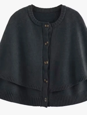 Svart stickad cape med knappar - Snygg svart stickad cape med rund halsringning och knäppning framtill med fem knappar. Capen har ribbade kanter och en avslappnad passform som ger en cool och trendig look. Perfekt att slänga över en hoodie eller tröja för extra stil.