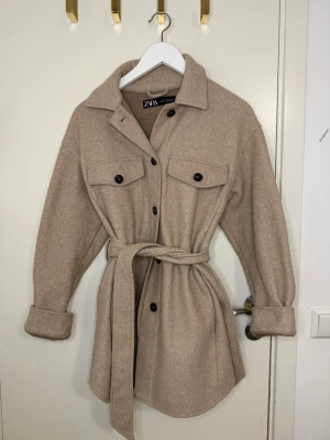 Beige overshirt från ZARA med bälte - Beige kappa från ZARA 🤍 Superfin passform med knyt i midjan. Perfekt till höst!