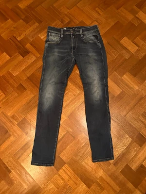 Mörkblå slim fit jeans - Snygga mörkblå slim fit jeans med klassisk femficksdesign och ljusa slitningar framtill. Jeansen har raka ben och kontrastsömmar. Perfekta för en avslappnad och trendig look. Materialet är troligtvis bomull med lite stretch för extra komfort. Sommen längst ner på högra benet har gått upp lite men de gör inte nån stor skillnad, skriv om ni har några frågor! 