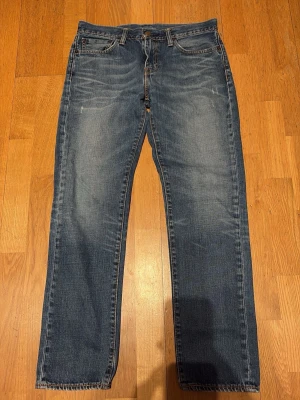 Blå raka jeans från Levi's - Klassiska blå jeans från Levi's med rak passform och fem fickor. Jeansen har en snygg tvätt med lätt slitning framtill och bakfickor med den ikoniska röda Levi's-detaljen. Tillverkade i slitstark denim, perfekta för en avslappnad stil.