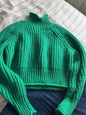 Grön ribbstickad polotröja från HM - Säljer en grön ribbstickad tröja med hög krage och långa ärmar. Tröjan har en croppad passform och är gjord i tjockt garn som ger en chunky känsla. Perfekt för dig som vill ha en färgklick i garderoben och gillar oversized stil.