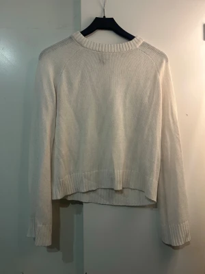 Vit stickad tröja med ribbade muddar - Klassisk vit stickad tröja med rund halsringning och långa ärmar. Tröjan har ribbade muddar vid ärmarna. Tröjan är åt det tunnare hållet!🌟