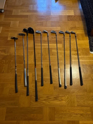 Golfklubbor set - Säljer ett set med 10 golfklubbor,  järn, wedgar, driver o hybrid  och putter. Klubborna har svarta och silverfärgade skaft och huvuden i metall. Perfekt för dig som vill börja spela golf eller behöver komplettera din utrustning. Höger klubbor. Mini bag ingår 