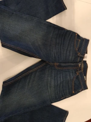 Mörkblå raka jeans med kontrastsömmar - Säljer ett par klassiska mörkblå jeans med raka ben och snygga kontrastsömmar. Jeansen har fem fickor och normal midja. Perfekta till en avslappnad stil och passar till det mesta i garderoben. Märke: Vailent. Innerbensmått: 81cm. Midjemått: ca 79cm. 