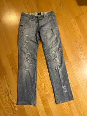Jeans m hål från D&G - Säljer dessa sjukt snygga Dolce Gabbana jeansen som är raka i benen med hål och stress både fram och bak. Super snygga och lågmidjade, säljer för att de tyvärr är för små på mig. Innerbernslängd är 85cm
