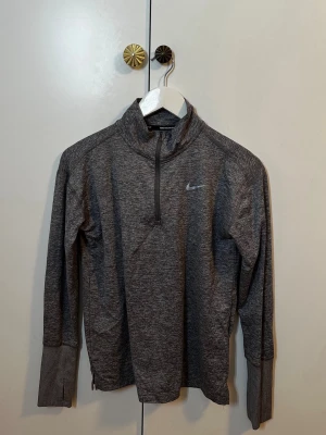 Nike Dri-FIT grå löpartröja - Säljer en grå långärmad löpartröja från Nike med halv dragkedja och hög krage. Storlek XS/S.