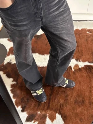 Svarta bootcut jeans med tvättade detaljer - Säljer ett par svarta bootcut jeans med snygga tvättade detaljer och lätt slitna partier. Jeansen har klassisk femficksmodell och raka, något utsvängda ben. Perfekta för dig som gillar en avslappnad och trendig stil.