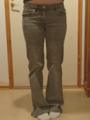jeans (dam)  - Ett par gråa jeans, low weist och lite bage. Lite slitna längst nere vid foten 