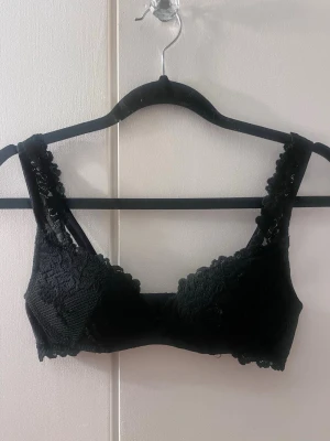 Svart spets-bh med breda axelband från Intimissimi storlek 70B - Snygg svart bh i spets med breda axelband, push up och dekorativa kanter. Bh:n har justerbara axelband och hakknäppning bak. Materialet är mjukt och stretchigt med fina spetsdetaljer både fram och bak. Perfekt för dig som gillar en feminin och bekväm stil. Från Intimissimi Den är storlek 70B men deras storlekar är så och passar nog bättre på någon med A kupa. 