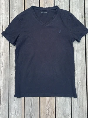 Svart v-ringad t-shirt Pier One - Klassisk svart t-shirt från Pier One med v-ringning och korta ärmar. Tillverkad i mjuk bomull för en skön känsla. Diskret logga broderad på bröstet. Perfekt basplagg till garderoben.