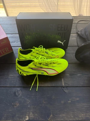 Puma Ultra gula fotbollsskor - Säljer ett par Puma Ultra fotbollsskor i neon-gult med svarta och blå detaljer samt vit Puma-logga. Mycket bra skick!