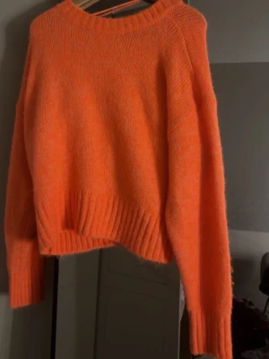Oversized orange stickad tröja - Säljer en  stickad tröja i stark orange färg. Tröjan har rund halsringning, långa ärmar och breda ribbstickade muddar vid ärmslut och nederkant. Perfekt för dig som gillar färg och vill ha en mysig, cool vibe.