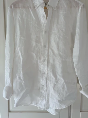 Vit linneskjorta från Cubus - Snygg vit skjorta i 100% linne från Cubus . Skjortan har klassisk krage, knappar framtill och lång ärm. Regular fit för en avslappnad men stilren look. Perfekt för varma dagar och enkel att styla till olika outfits.
