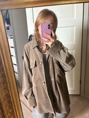 Beige overshirt i manchester  - Säljer en beige overshirt i manchestertyg med stora bröstfickor och knappar framtill. Overshirten har avslappnad passform, klassisk krage och långa ärmar. 