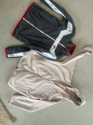 Beige fleecejacka från 157 - Mysig beige fleecejacka från 157 med dragkedja framtill och två fickor med dragkedja. Perfekt för lager på lager och har en enkel, stilren design med huva. Passar dig som gillar bekväma och funktionella plagg.