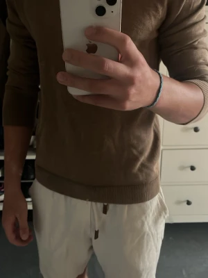 Brun stickad tröja från Bläck - Snygg brun stickad tröja från Bläck med rund halsringning och ribbade muddar vid ärmslut och nederkant. Perfekt basplagg i garderoben, enkel att matcha till olika outfits. Materialet känns mjukt och bekvämt. bara lite skrynklig för den har legat i en låda
