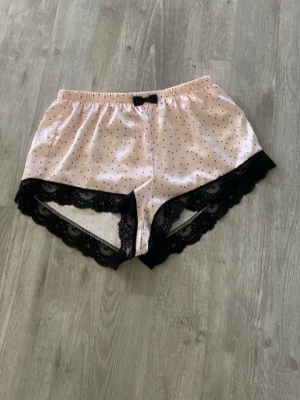 Pyjamas shorts  - Rosa shorts med svarta prickar och spets vid benen. 