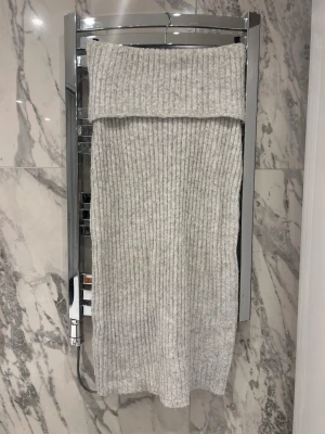 Ljusgrå ribbad stickad långkjol - Mysig ljusgrå långkjol i ribbstickat material med bred, vikt midja. Perfekt att matcha med en stickad tröja för en snygg outfit.