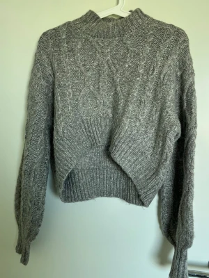 Crop tröja Primark - Croppad grå kabelstickad tröja från Primark med  något högre hals och ribbade muddar. Den är dock lite stickig så använd långärmad tröja under för att undvika! T