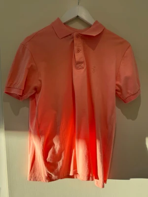 Rosa pikétröja från Polo Ralph Lauren - Säljer en klassisk rosa pikétröja från Polo Ralph Lauren. Tröjan har korta ärmar, krage och knappar framtill. Tillverkad i mjuk bomull och har en diskret broderad logga på bröstet. Perfekt för en avslappnad men ändå stilren look.