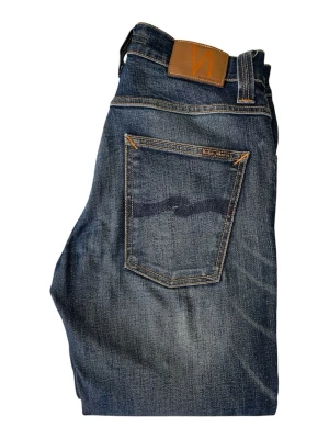 Mörkblå jeans från Nudie Jeans - W31 men passar 30 .Snygga mörkblå jeans från Nudie Jeans med klassisk femficksdesign och raka ben. Jeansen har slitningar och kontrastsömmar samt en läderpatch med logga bak i midjan. Perfekta för en avslappnad och trendig look.