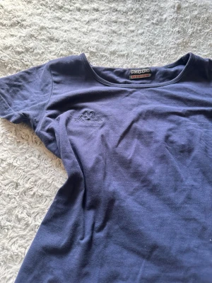 Marinblå t-shirt från Kappa - Snygg marinblå t-shirt från Kappa med klassisk rund halsringning och diskret broderad logga på bröstet. Tillverkad i mjuk bomull som känns skön mot huden. Ståf ingen stolek men passar som en  S.