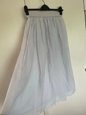 Ljusvit långkjol med resår - Lång, ljusvit kjol med bred resår i midjan. Kjolen har ett luftigt och flowigt material som ger en avslappnad känsla. Perfekt för dig som gillar en enkel och stilren look. Passar till sneakers eller sandaler.