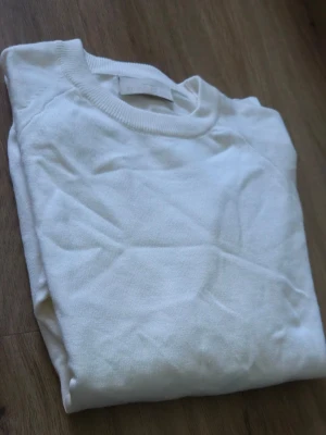 Vit tröja från Stone Island - Säljer en stilren vit tröja från Stone Island med klassisk rund hals och ribbade muddar. Tröjan har den ikoniska Stone Island-loggan på ärmen och är tillverkad i mjukt material som känns skönt mot huden. Perfekt för dig som gillar minimalistisk och clean stil. Det är en ovanlig design med de vita märket på armen