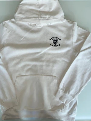 Hoodie Seventh avenue  - Säljer en fin och bekväm hoodie från H&M i en ljus, off-white färg. Tröjan har en snygg "Seventh Avenue"-grafik tryckt på ryggen och en mindre logga på bröstet. Storlek: 146/152 (motsvarar ca 10-12 ăr). Detaljer: Mjukt och skönt foder pa insidan. Skick: Sparsamt använd och i fint skick. Hör gärna av dig om du har nagra fragor eller vill se fler bilder!