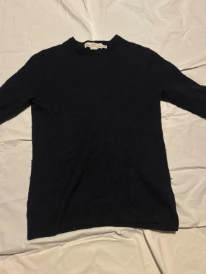 Svart stickad tröja från H&M L.O.G.G. - En enkel och stilren svart stickad tröja från H&M L.O.G.G. med rund halsringning och långa ärmar. Tröjan har ribbade muddar vid ärmslut och nederkant, perfekt för lager på lager och en clean look. Passar även bra som xs