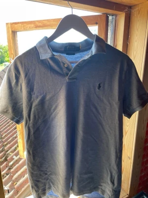 Ljusblå pikétröja från Polo Ralph Lauren - Snygg Ljusblå pikétröja från Polo Ralph Lauren med klassisk krage, två knappar och broderad logga på bröstet. Modellen är custom slim fit och tillverkad i mjuk bomull som känns skön mot huden. Perfekt till jeans eller shorts för en clean look.
