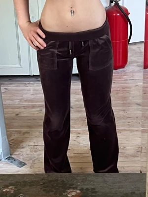 Juice Couture Byxor - Säljer ett par bruna Juice Couture byxor då de tyvärr är för långa på mig som är 160. Jag har aldrig använt dom, men köpte dom på Vinted från en tjej som använt dem ett fåtal gånger. Byxornas nyans på bilderna skiftar sig lite pga olika ljus. Jag har vikt ner midjan på bilderna, så att de sitter lägre. Jag skulle tro att dom sitter längdmässigt bra på dig som är 165-170 cm lång. Dom är i väldigt bra skick, nästan som nya! Hör av dig vid fler frågor eller exakta mått! Kolla gjärna min profil 😊