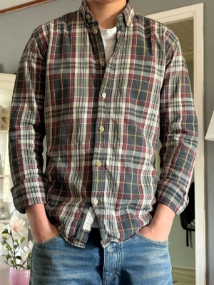 Rutig skjorta från selected Homme - Klassisk rutig skjorta från Selected Hommei mjuk bomull. Skjortan har knappar framtill, button-down krage och långa ärmar. Färgkombinationen är mörkblå, vinröd, vit och gul. Perfekt till jeans för en avslappnad men snygg stil.