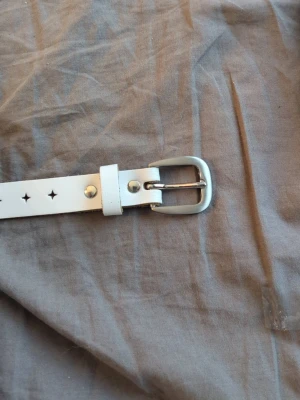 Vitt läderbälte med stjärnhål - Snyggt vitt bälte i äkta läder med stjärnformade hål och silvrigt spänne. Bältet är tillverkat i Gnosjö och har en stilren design som passar till många outfits. Perfekt accessoar för att lyfta din look.