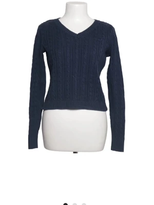Mörkblå stickad tröja Hollister - Mörkblå stickad tröja från Hollister med v-ringning och kabelstickat mönster. Tröjan har långa ärmar och ribbade muddar vid ärmslut och nederkant. Perfekt för lager-på-lager och enkel att matcha med jeans eller kjol.