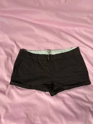 Bruna shorts - Stilrena bruna shorts från Jeanswear i en trendig lågmidjad modell. Klassisk design som passar perfekt till både vardag och sommaroutfits. Shortsen har en enkel och clean look som gör dem lätta att matcha med toppar, hoodies eller linnen för en Y2K-inspirerad stil. 