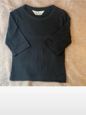 Svart tight topp från H&M - En enkel och stilren svart topp från H&M med tight passform och halvlånga ärmar. 💗