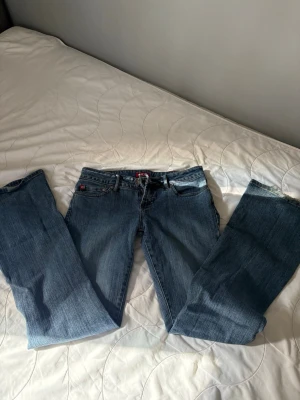 Blåa bootcut jeans från tinesell - Säljer ett par blåa bootcut jeans från Esotiq, tinesell med snygga guldiga broderier på bakfickorna. Klassisk femficksmodell med låg midja och bälteshällor. Jeansen är i mjukt denimtyg och har en avslappnad passform som ger en cool vibe. Köpte för 600!❤️